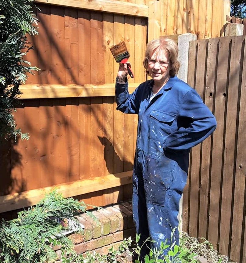 Pat Bennett, painting a fence in her garden