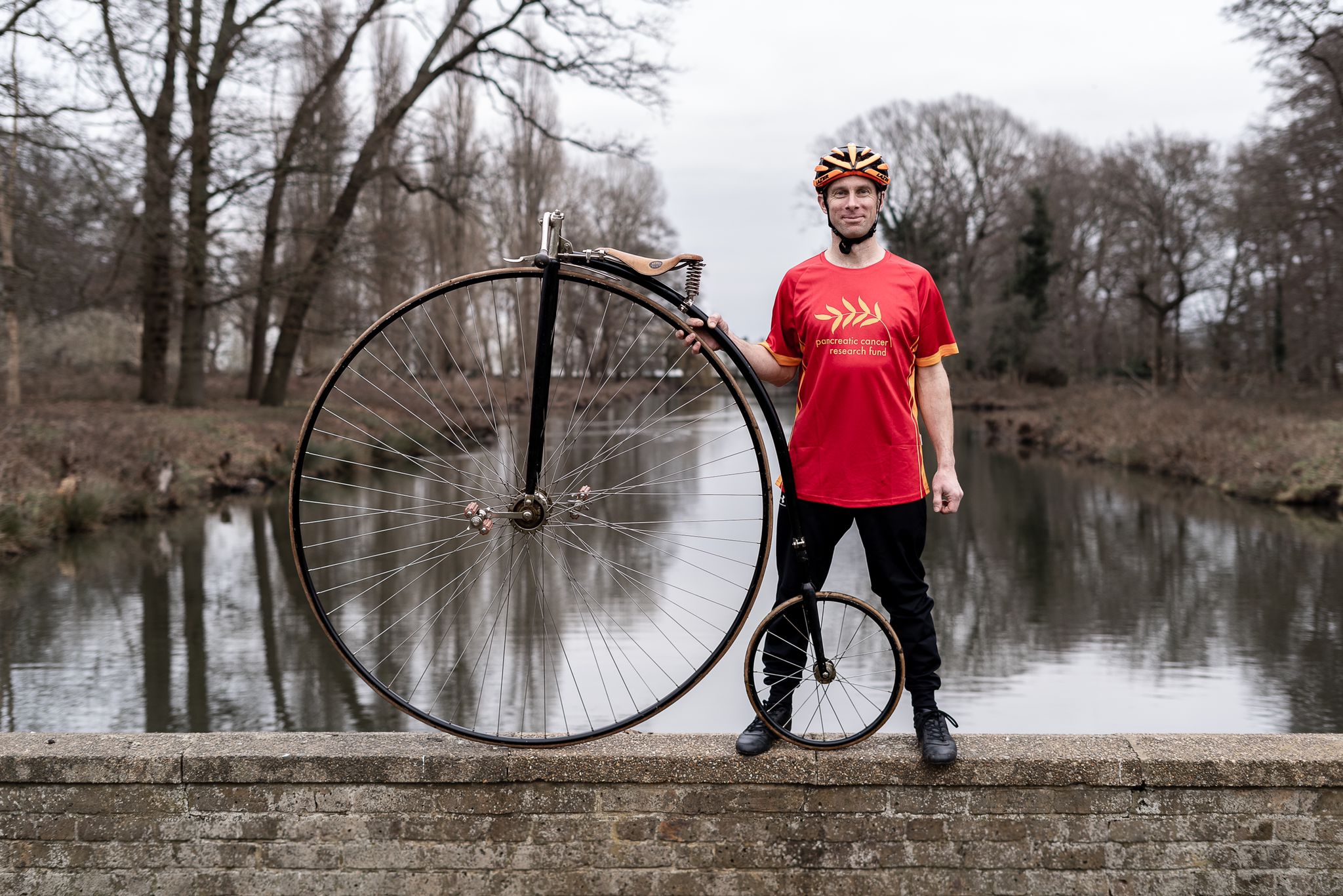 Michael Gray stands with Penny Farthing wearing PCRF T-shirt